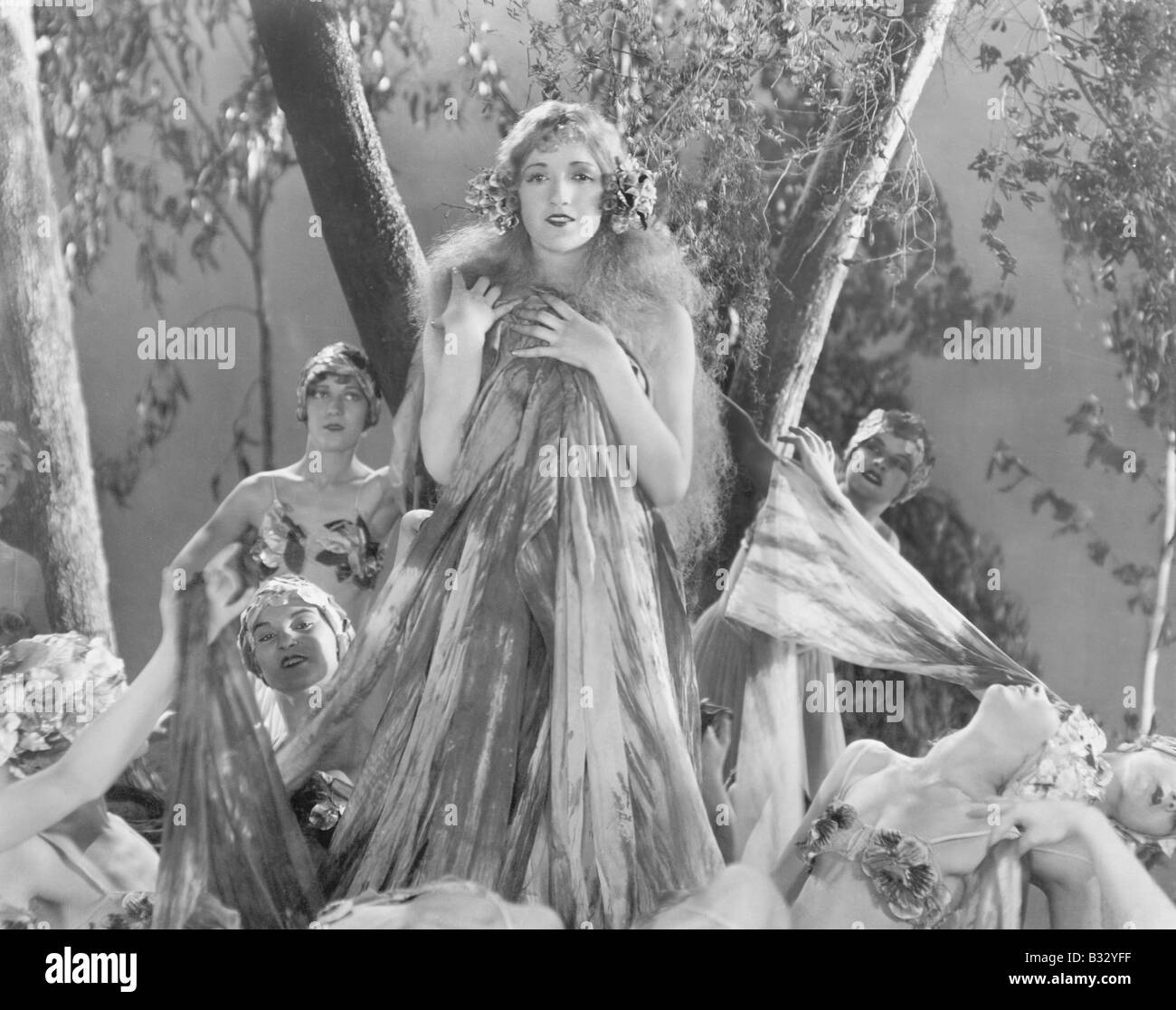 Gruppe von Frauen gekleidet in Seide und Blumen stehen im Zauberwald Stockfoto