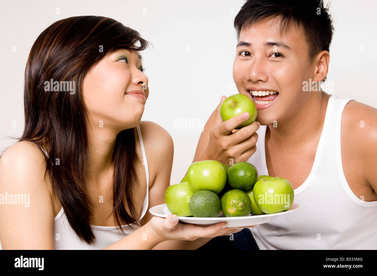 Ein junger asiatischen Mann isst gerne einen grünen Apfel angeboten, ihn von seiner hübschen Freundin Stockfoto