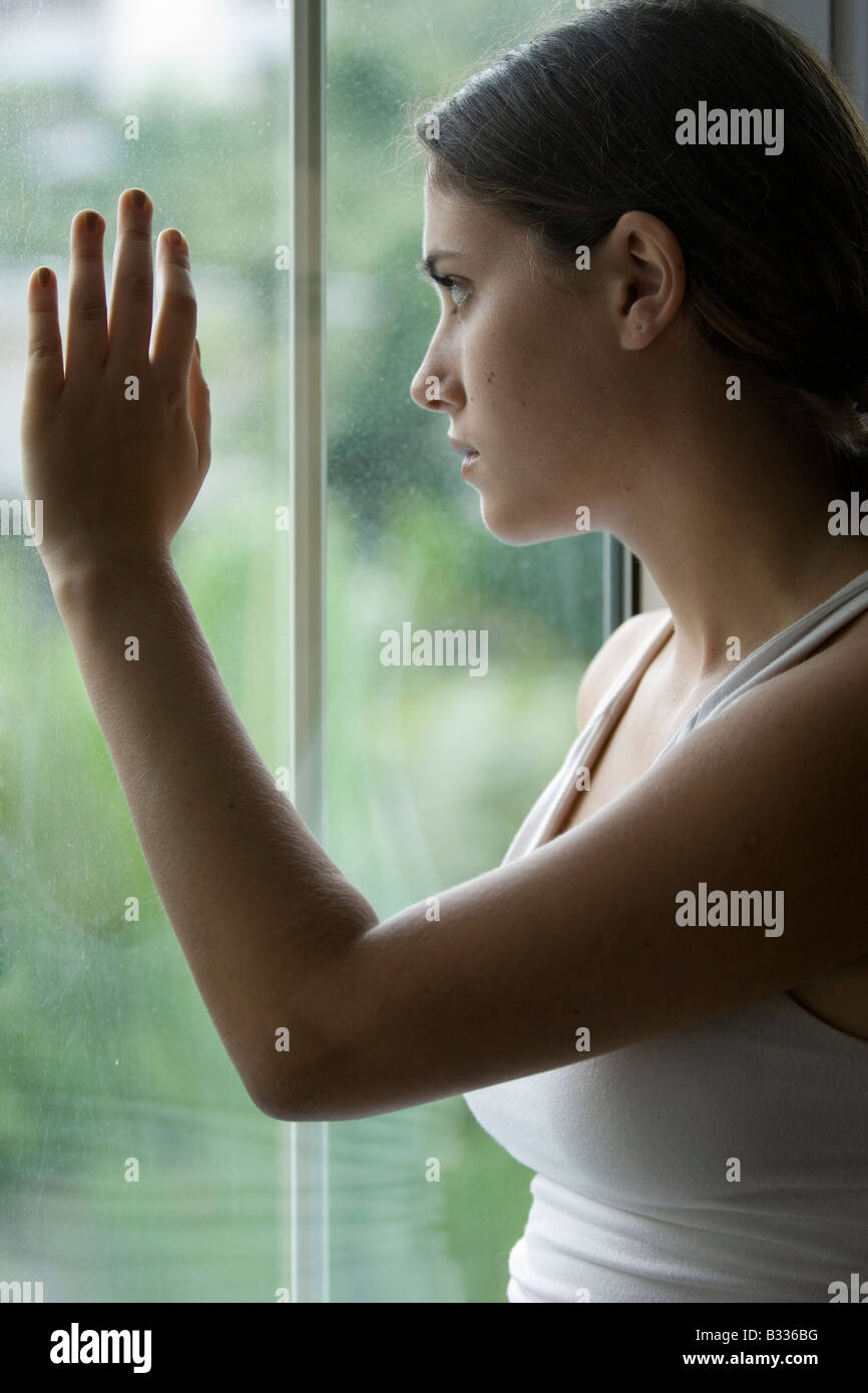 Eine junge Frau schaut aus dem Fenster in eine Welt der eigenen Stockfoto