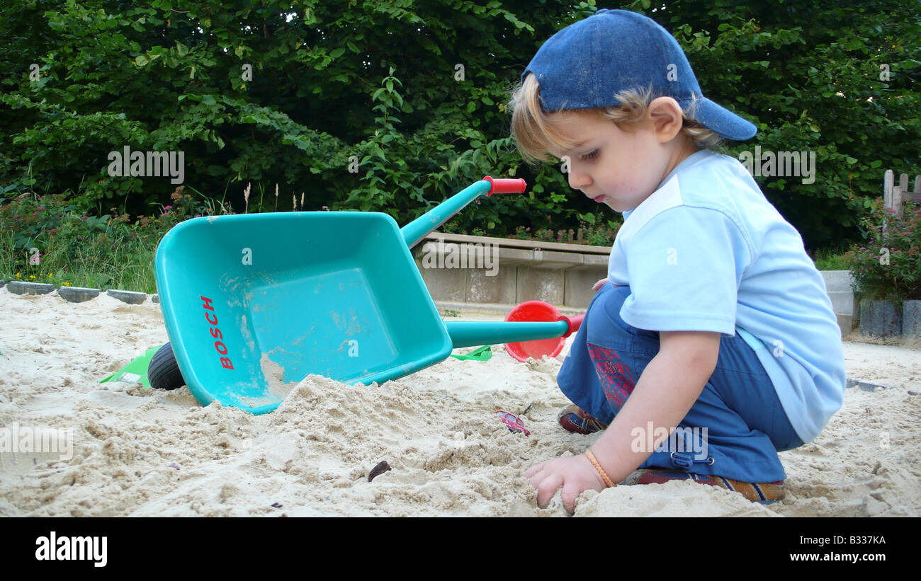 kleiner Junge in einer Sandbox Spiel mit Hand barrow Stockfoto