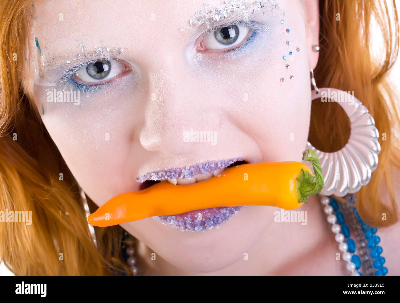 heiße rothaarige Frau mit Chili in Mund Stockfoto