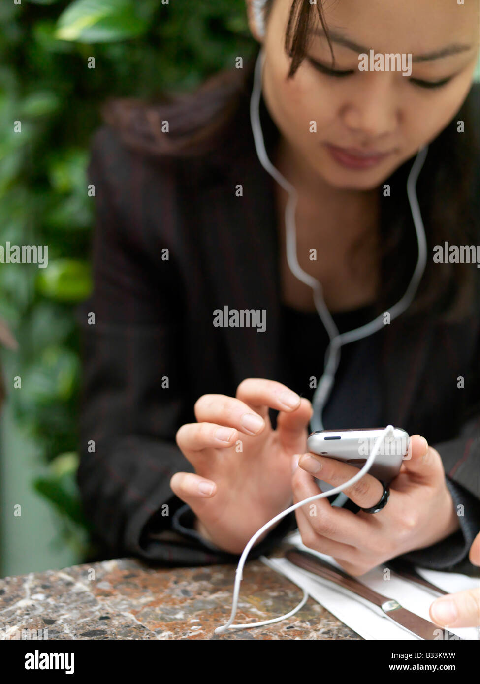 Eine junge Frau hört ihr Handy bei der Auswahl aus der Touch-screen Stockfoto