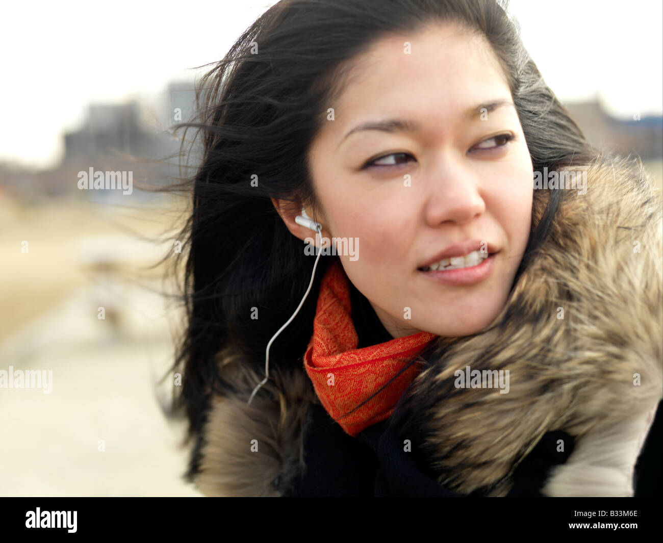 Eine junge Frau mit Wind fegte schaut Weg, während Sie Musik hören. Stockfoto