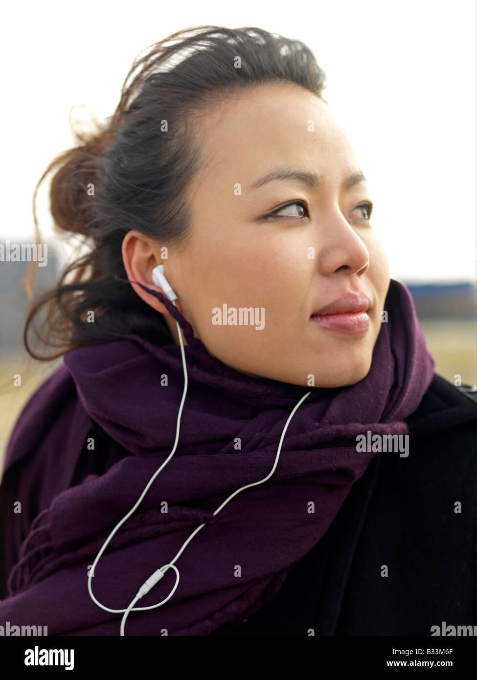 Eine junge Frau mit Wind fegte schaut Weg, während Sie Musik hören. Stockfoto
