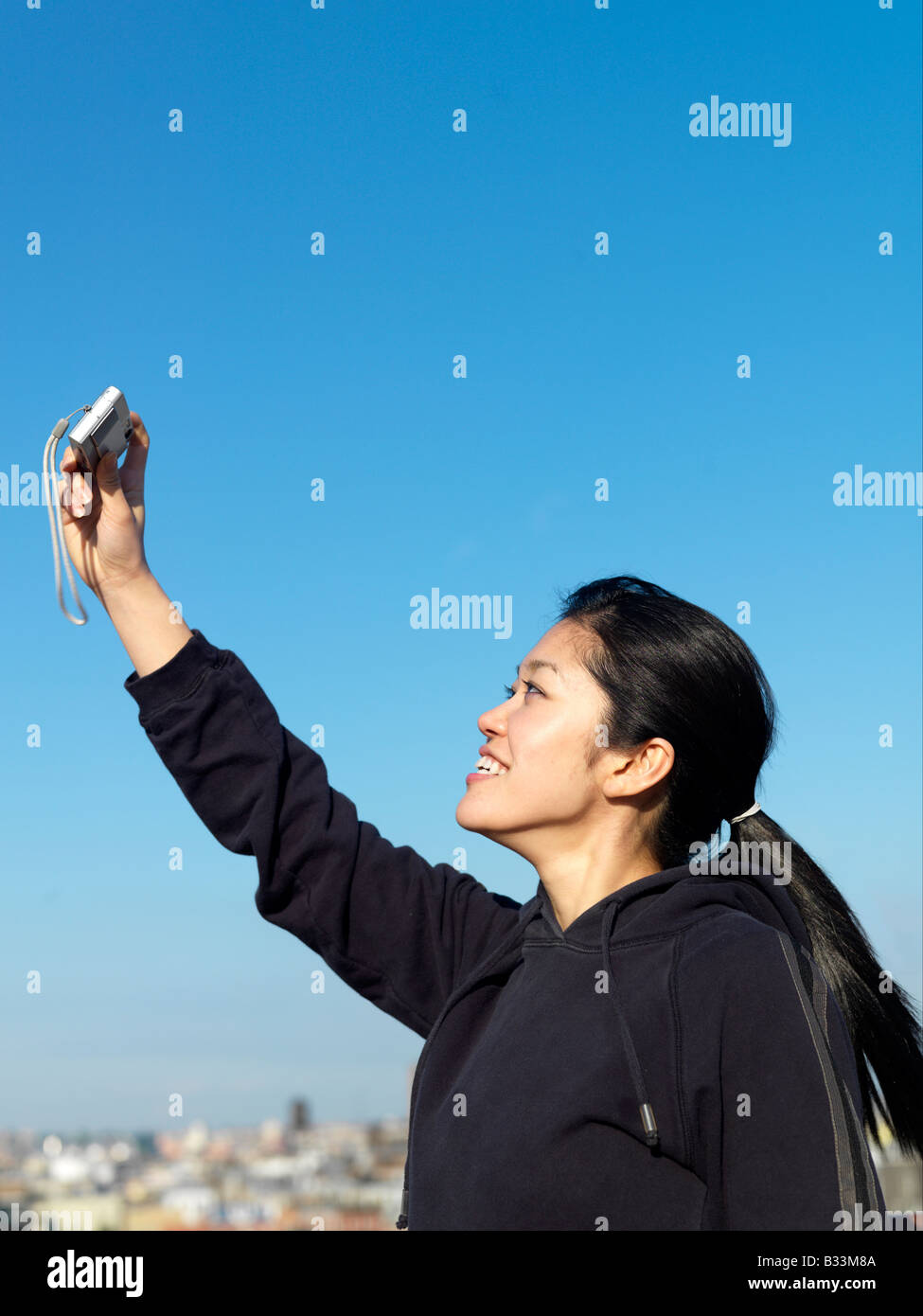 Eine junge asiatische Frau nimmt Selbstporträts mit einem Mobiltelefon Stockfoto