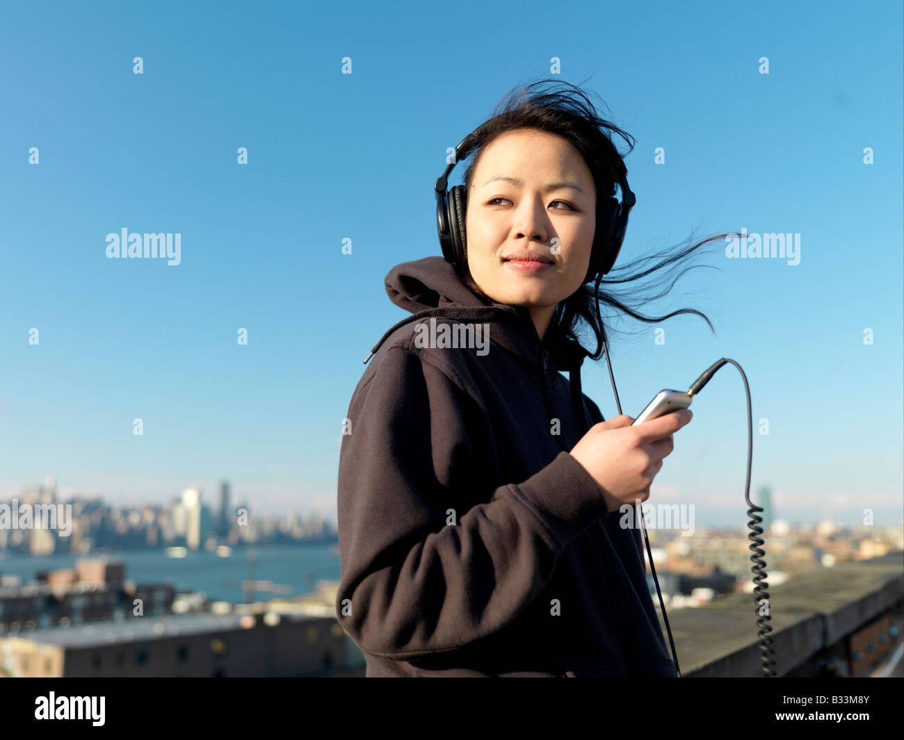 Eine junge Asiatin hört Musik auf einem Handheld-Gerät. Stockfoto