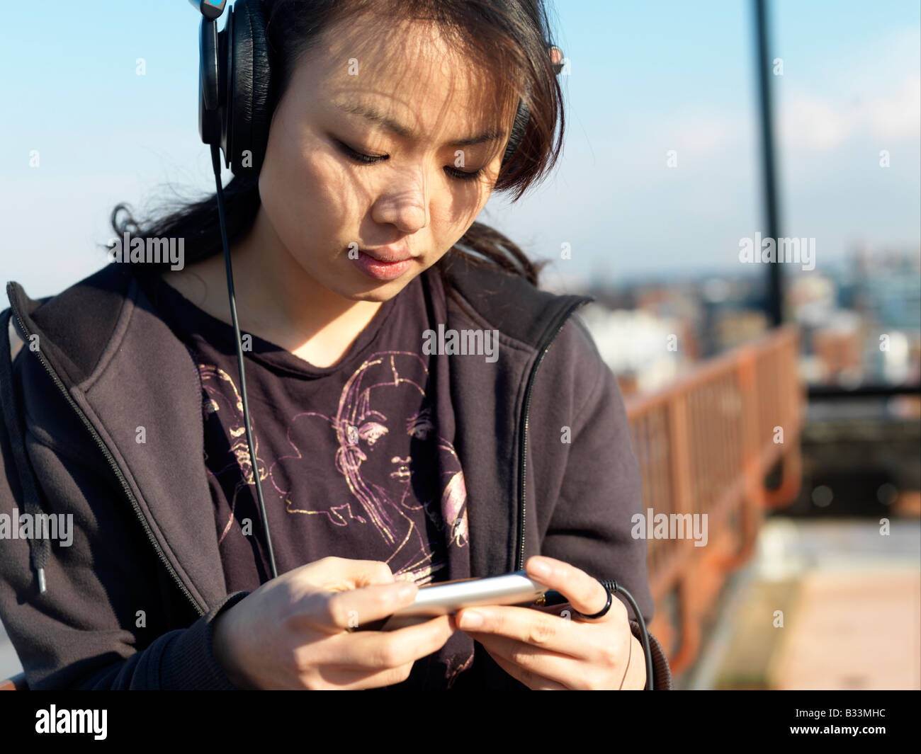 Eine junge Frau, hören Sie Musik auf ihrem Handy Stockfoto