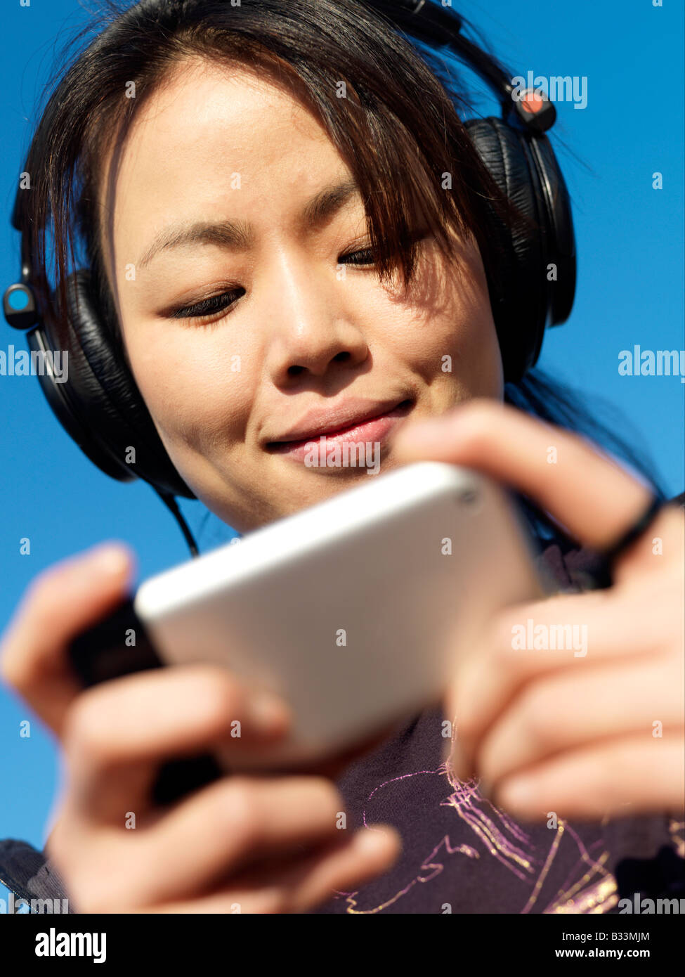 Eine junge Frau, hören Sie Musik auf ihrem Handy Stockfoto