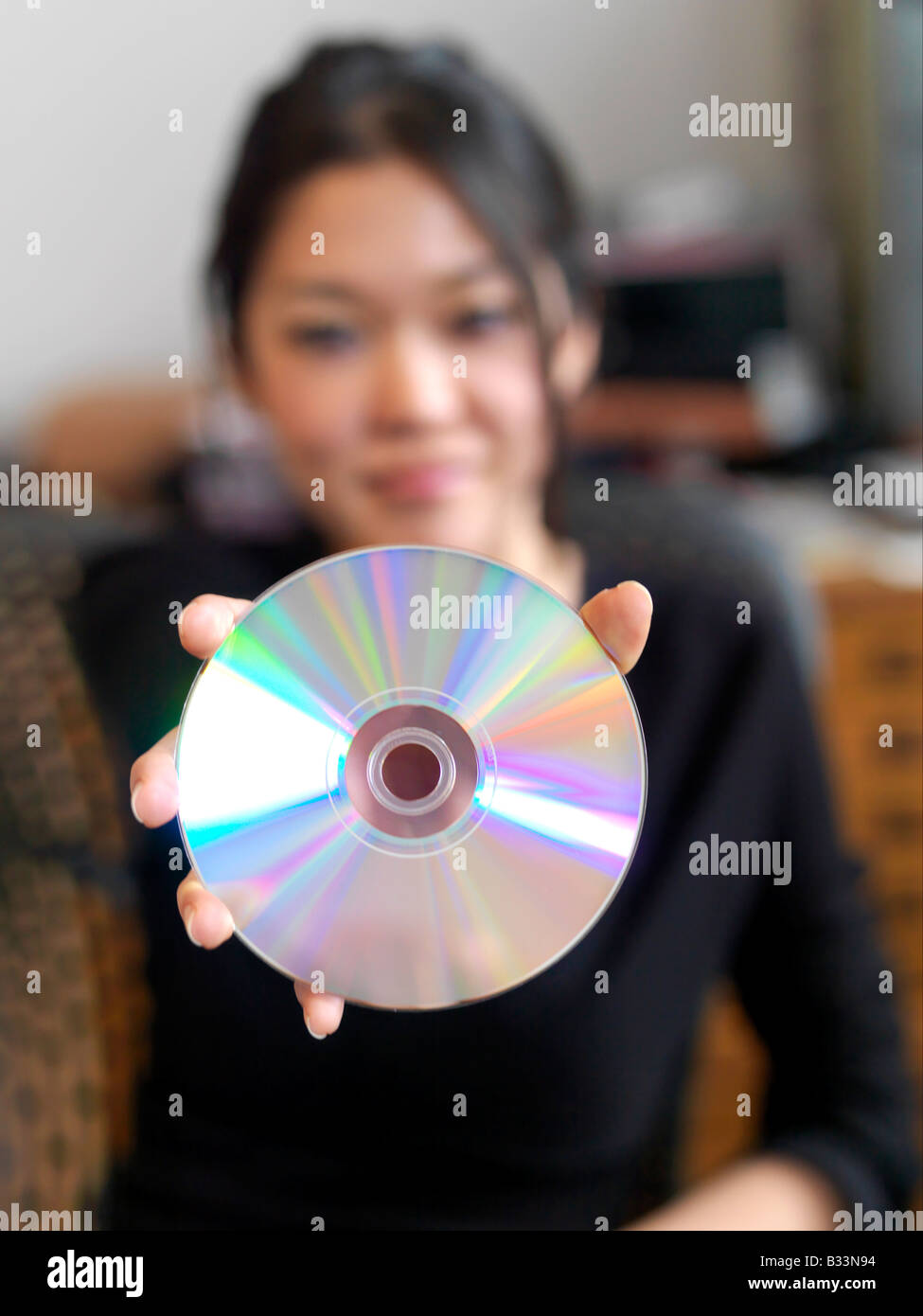 Eine Nahaufnahme einer lächelnden jungen asiatischen Frau hält eine CD Stockfoto