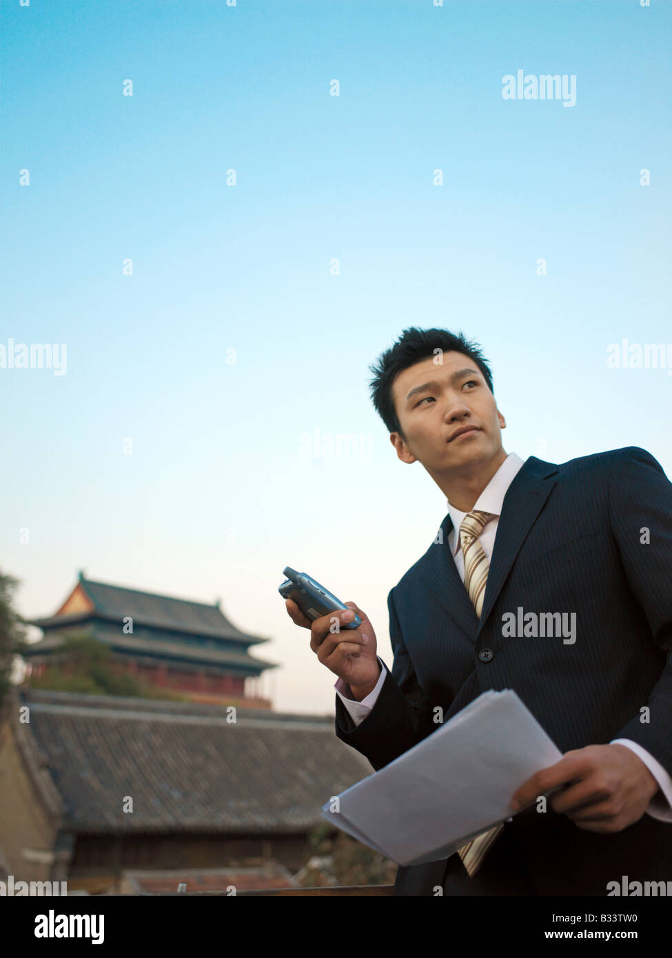 Chinesischer Unternehmer einige Dokumente überprüfen und mit seinem Handy für geschäftliche Zwecke. Stockfoto