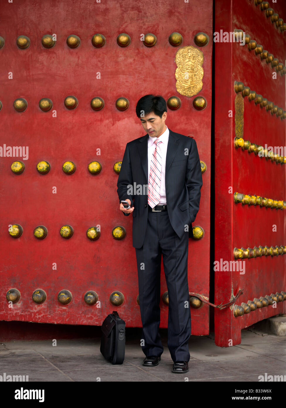 Ein chinesischer Geschäftsmann mit seinem Mobiltelefon für seine Zwecke nutzen als auch Geschäftsreisende. Stockfoto