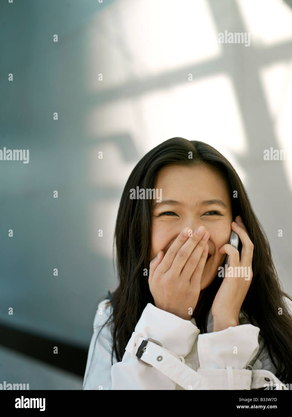 Eine junge chinesische Geschäftsfrau mit ihrem Handy PDA in der Stadt Stockfoto