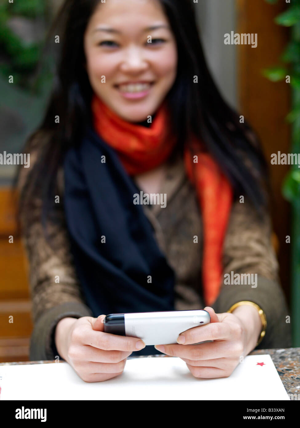 Eine junge asiatische Frauen hält ein Handy beim Lachen Stockfoto