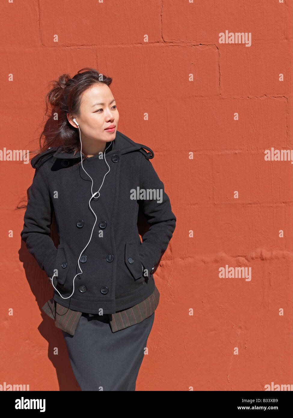 Eine junge Frau, Musik hören, eine bunte Wand gelehnt. Stockfoto