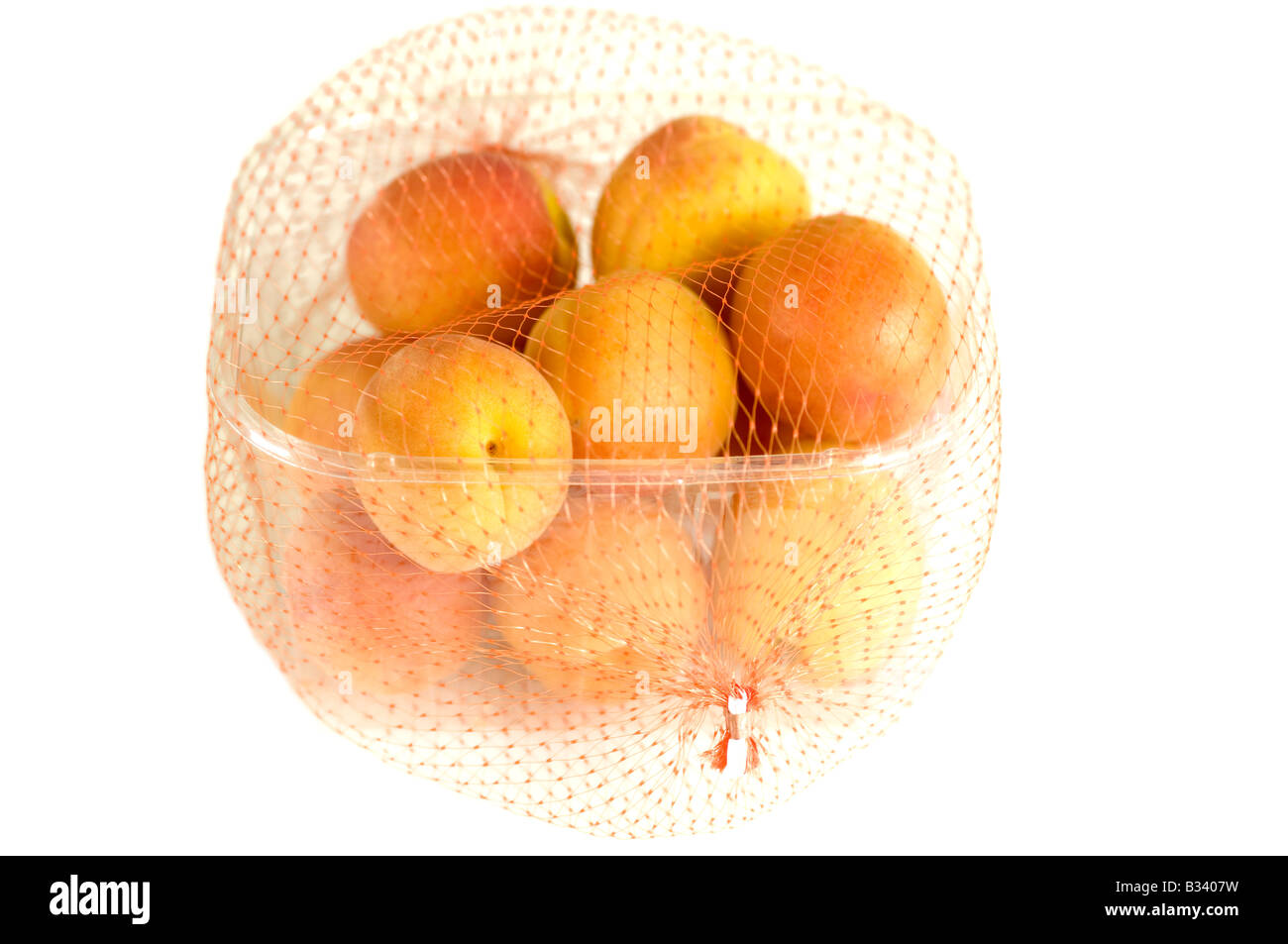 Aprikosen in eine Plastik Körbchen mit Orange Netz Abdeckung Stockfoto