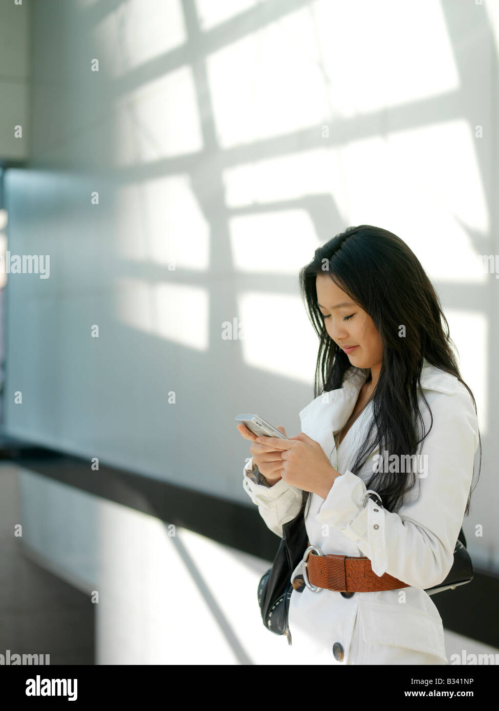 Eine junge chinesische Geschäftsfrau mit ihrem Handy PDA in der Stadt. Stockfoto