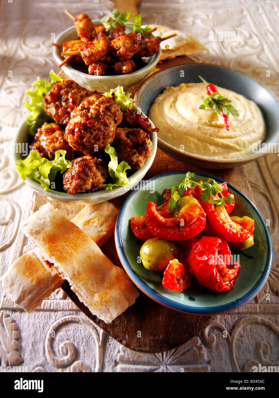 BBQ Party Essen - von vorne - Sonne errötete Tomaten, Lamm Kofta, Hummus, Mini marinierte Hähnchenspieße mit Pitta-Brot Stockfoto