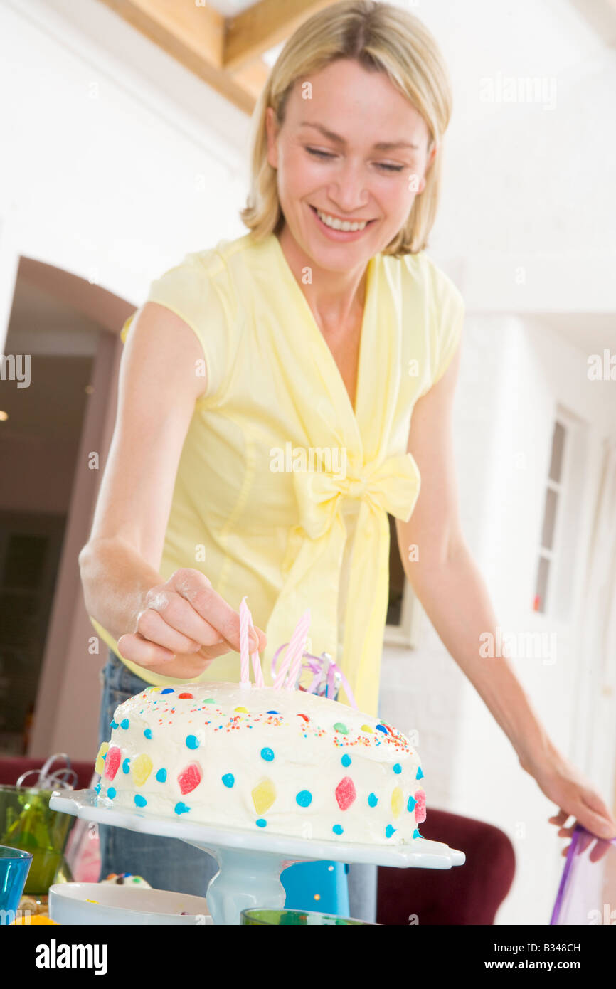 Frau setzen Kerzen im Kuchen lächelnd Stockfoto