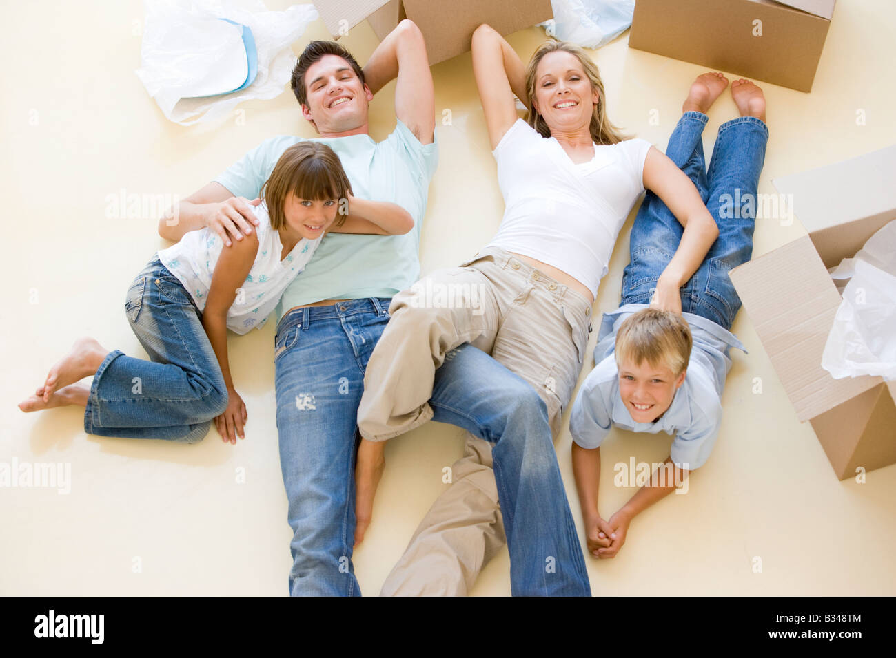 Familie im neuen Hause lächelnd am Boden durch offene Boxen liegend Stockfoto