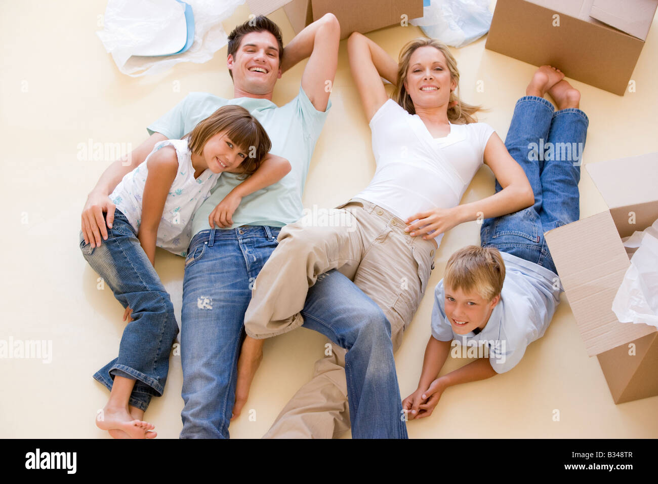 Familie im neuen Hause lächelnd am Boden durch offene Boxen liegend Stockfoto