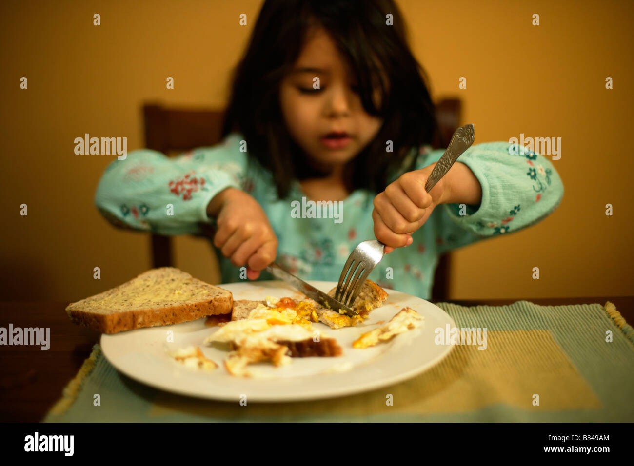 Lernen, benutzen Sie ein Messer und Gabel ein Fünf Jahres altes Mädchen isst Spiegelei auf toast Stockfoto