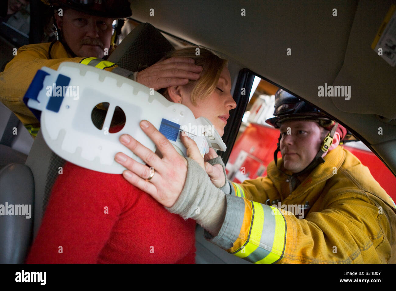 Zwei Feuerwehrleute helfen Frau mit Nackenschutz Stockfoto