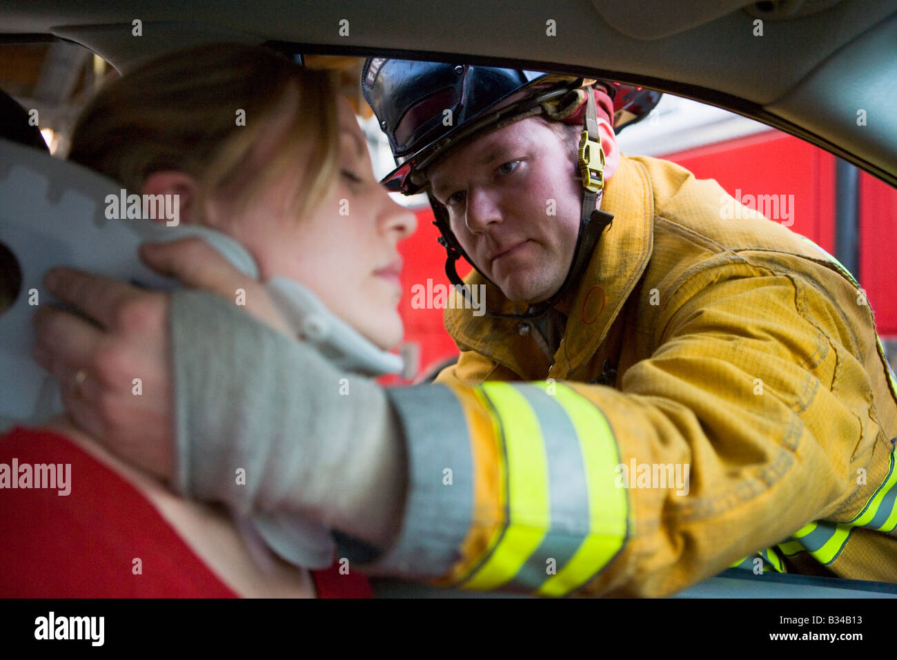 Feuerwehrmann hilft Frau mit Nackenschutz (Tiefenschärfe) Stockfoto