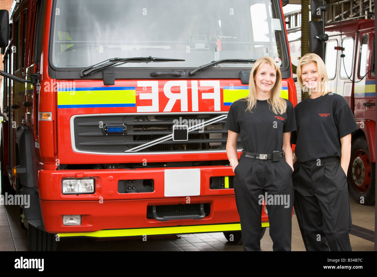 Zwei Feuerwehrleute stehen vor Feuerwehrauto Stockfoto