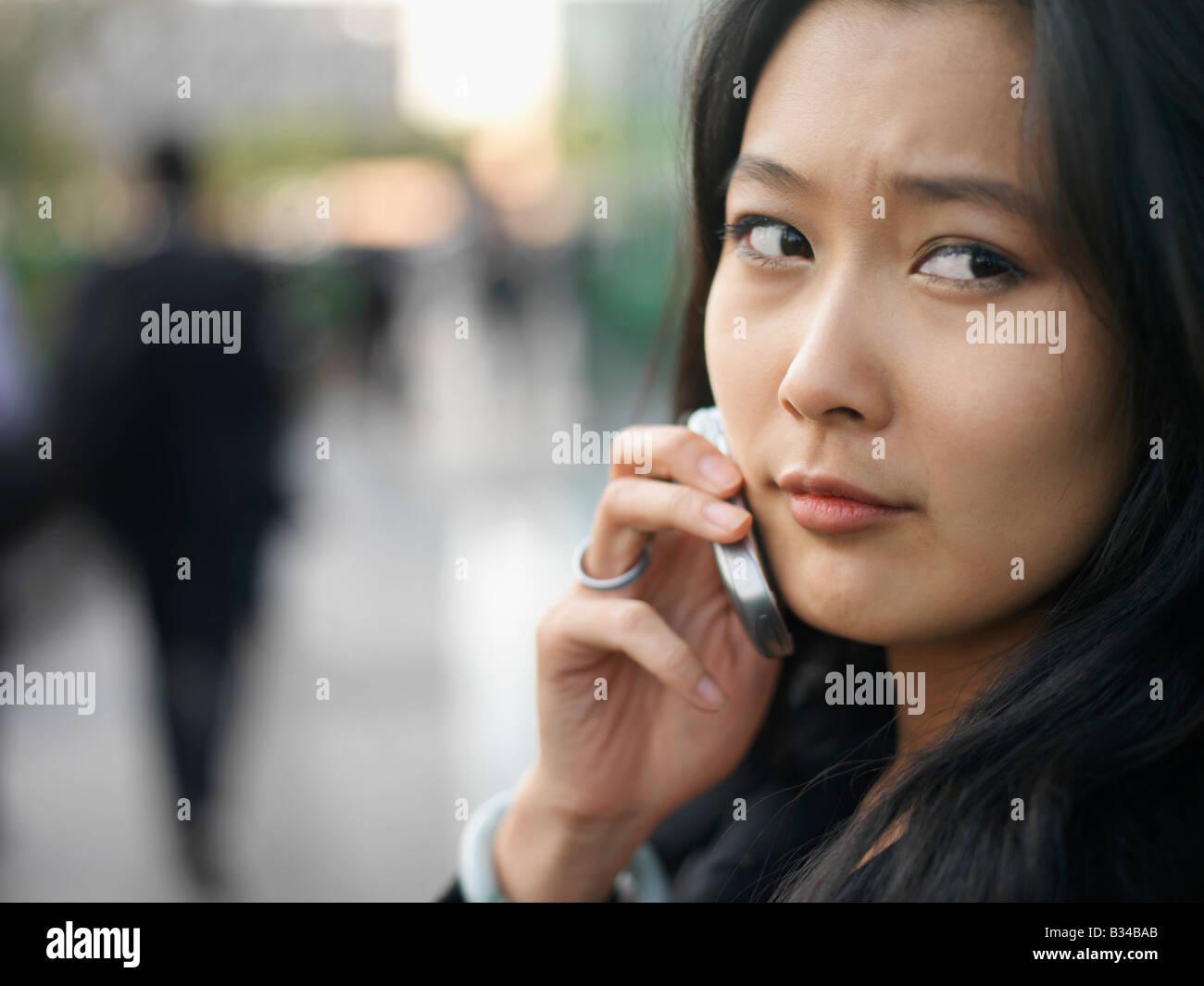 Eine junge chinesische Geschäftsfrau mit ihrem Handy in der Stadt. Stockfoto