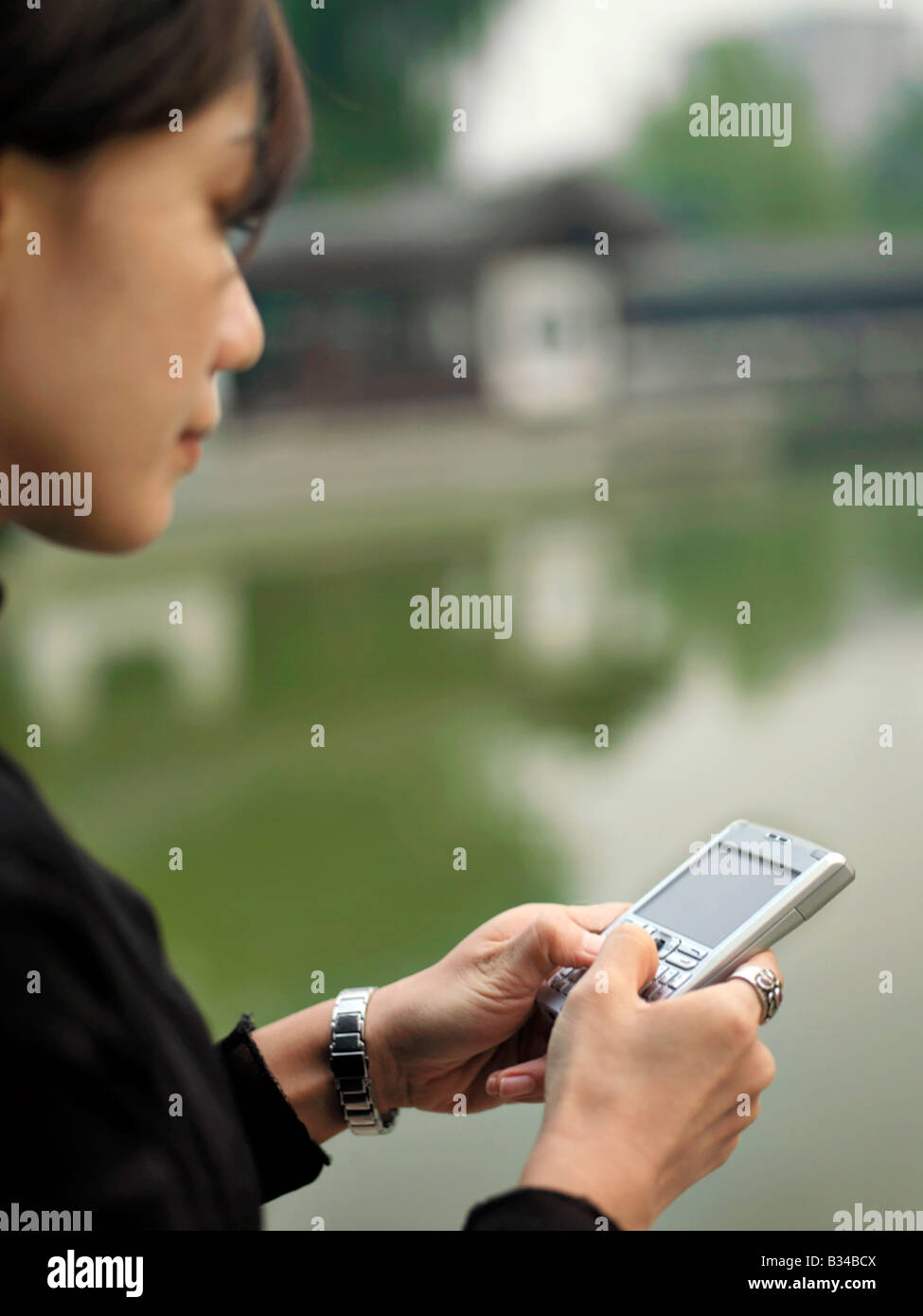 Eine chinesische Geschäftsfrau mit ihrem Mobiltelefon mit chinesischer Architektur im Hintergrund Stockfoto