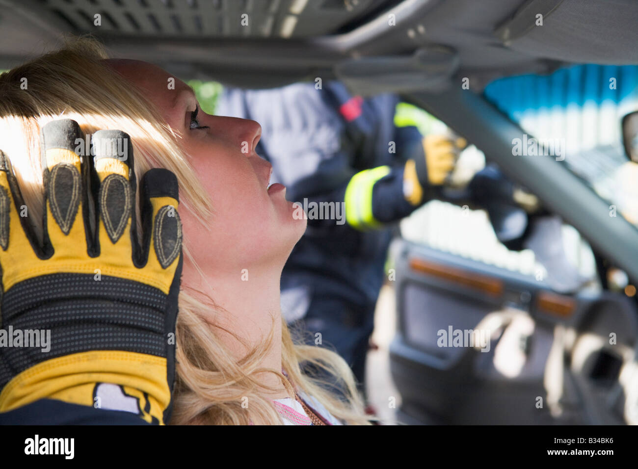 Verletzte Frau in Auto mit Feuerwehrmann im Hintergrund ausschneiden Windschutzscheibe (Tiefenschärfe) Stockfoto