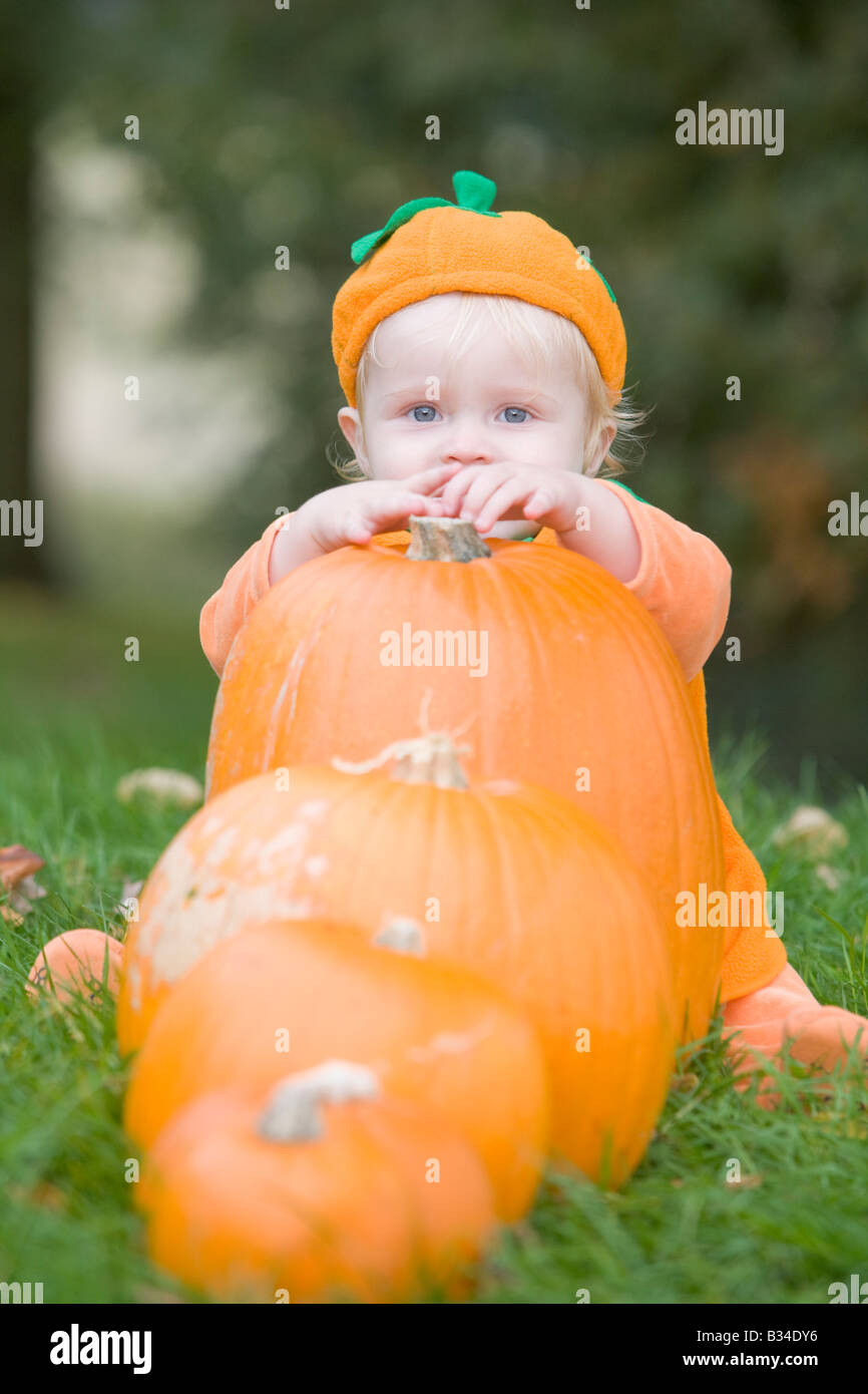 Baby Boy im Freien in Kürbiskostüm mit echten Kürbisse Stockfoto