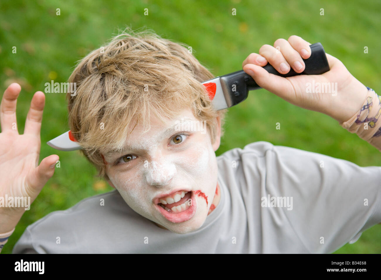 Junge mit scary Halloween Make-up und Kunststoff-Messer durch den Kopf Stockfoto