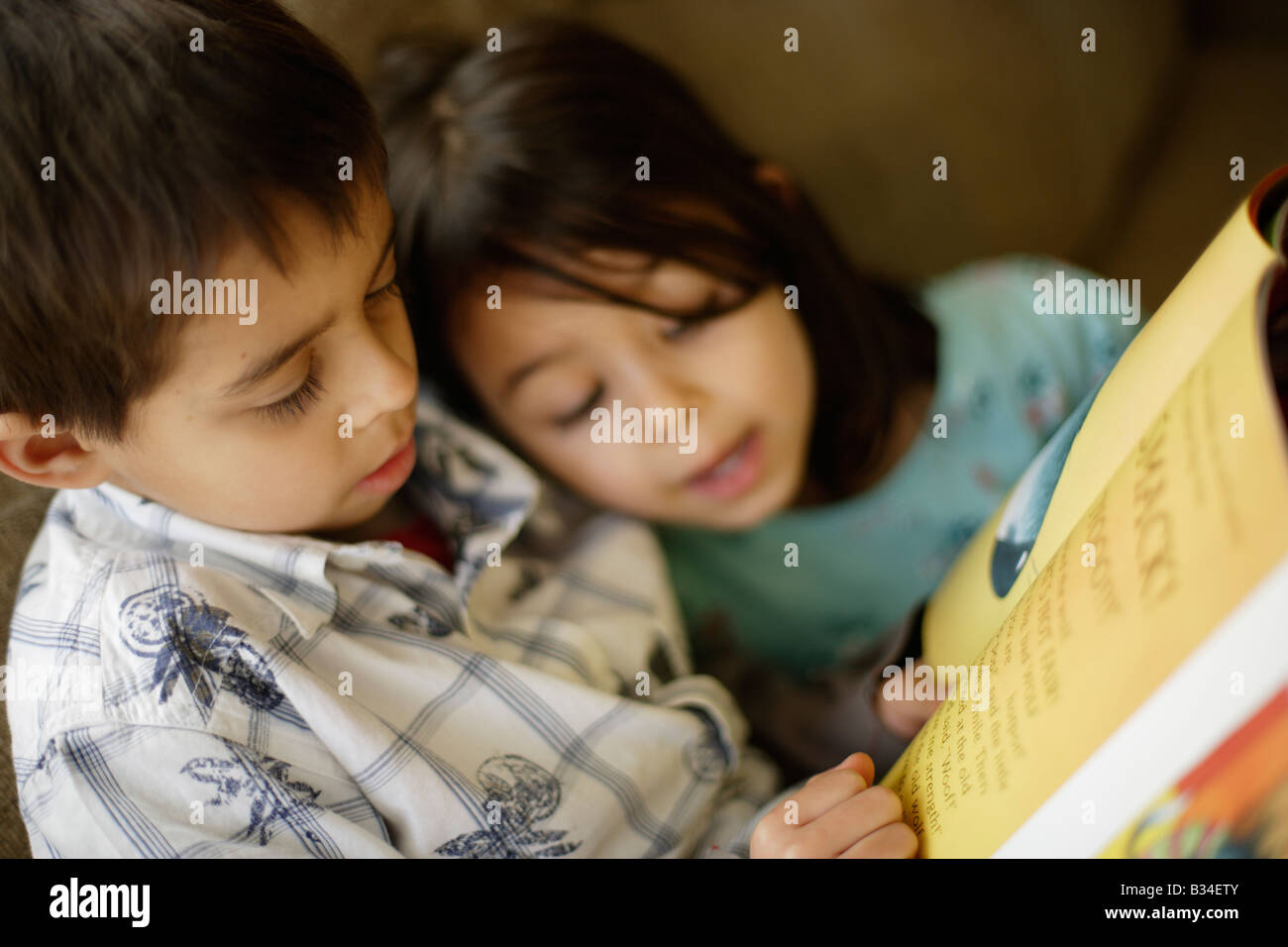 Jungen im Alter von sechs Jahren liest eine Geschichte um seine kleine Schwester im Alter von fünf Jahren Stockfoto
