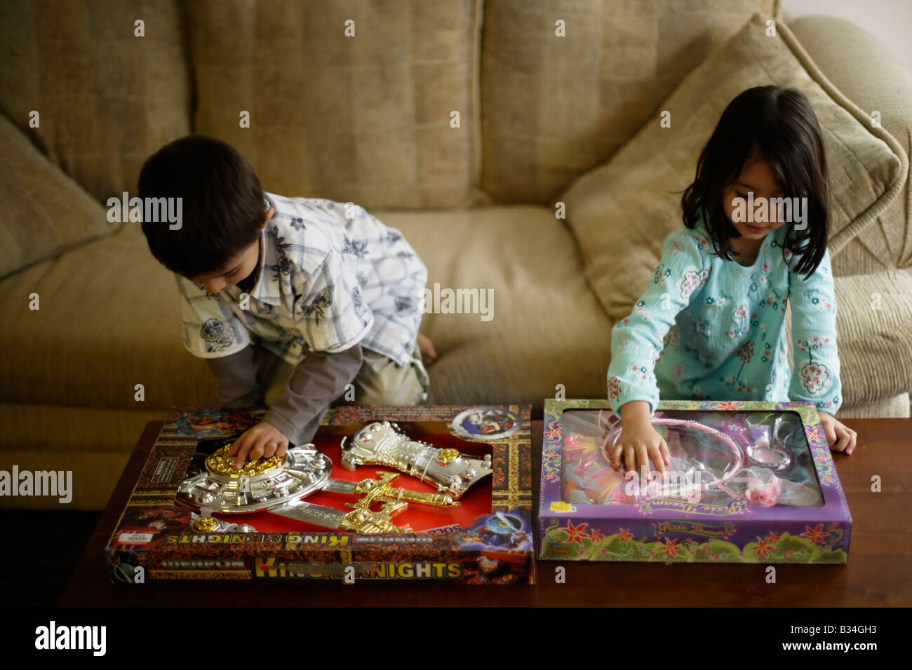 Jungen im Alter von sechs und Schwester fünf mit neuen Box Spielzeug Kunststoff Rüstung für ihn Fee Kostüm für sie Stockfoto