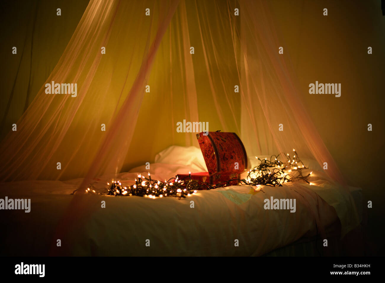 Offener Kasten mit Lichtern auf Bett mit Baldachin Stockfoto