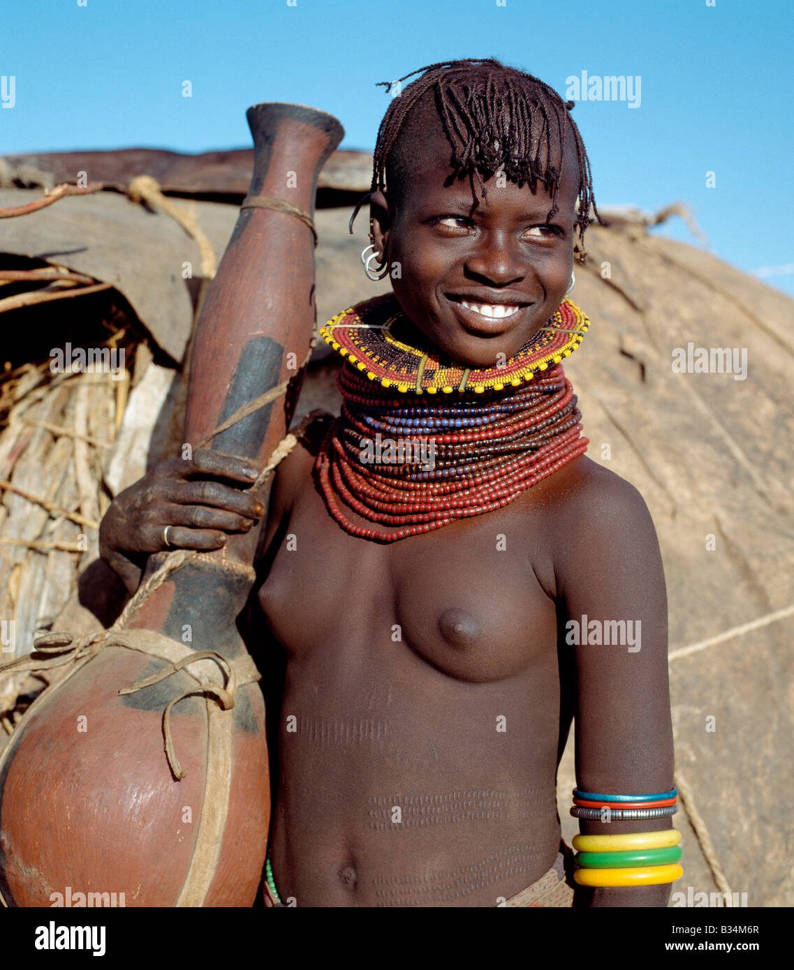 Kenia, Baragoi, Nachola. Ein Turkana-Mädchen mit einem großen Kürbis-wie Behälter als ein Gefäß für Wasser oder Milch verwendet. Bei fehlender Kürbisse Schnitzen die Turkana ihre Container aus Weichholz, wie Sie von den gemeinsamen Commiphora-Arten, die in semi-ariden Land lebt. Stockfoto