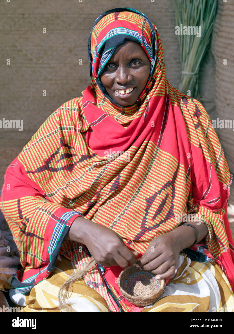 Kenia, Küstenprovinz, Lamu Insel. Eine Pokomo Frau in helle Baumwollkleidung macht einen kleinen geflochtenen Korb. Die Pokomo Menschen sind Bantu Herkunft und Leben an den Ufern des Tana River südwestlich von Lamu. Stockfoto