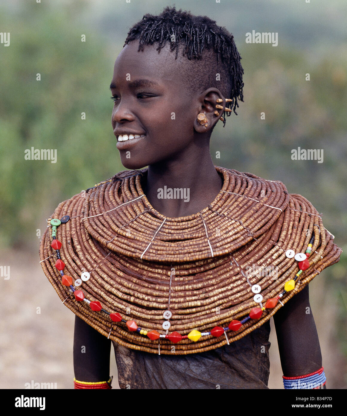 Kenia, Baringo, Nginyan'g. Ein junges Pokot Mädchen in traditioneller Kleidung. Mädchen tragen Leder-Röcke und Capes aus Haus gegerbt Ziegenfelle hergestellt. Ihre breiten Ketten bestehen aus kleinen Segmenten Segge Gras. Ihre Ohren haben bereits durchbohrt, an vier Orten, die große Messing-Ohrringe einfügen, die sie nach der Heirat erwerben wird. Stockfoto