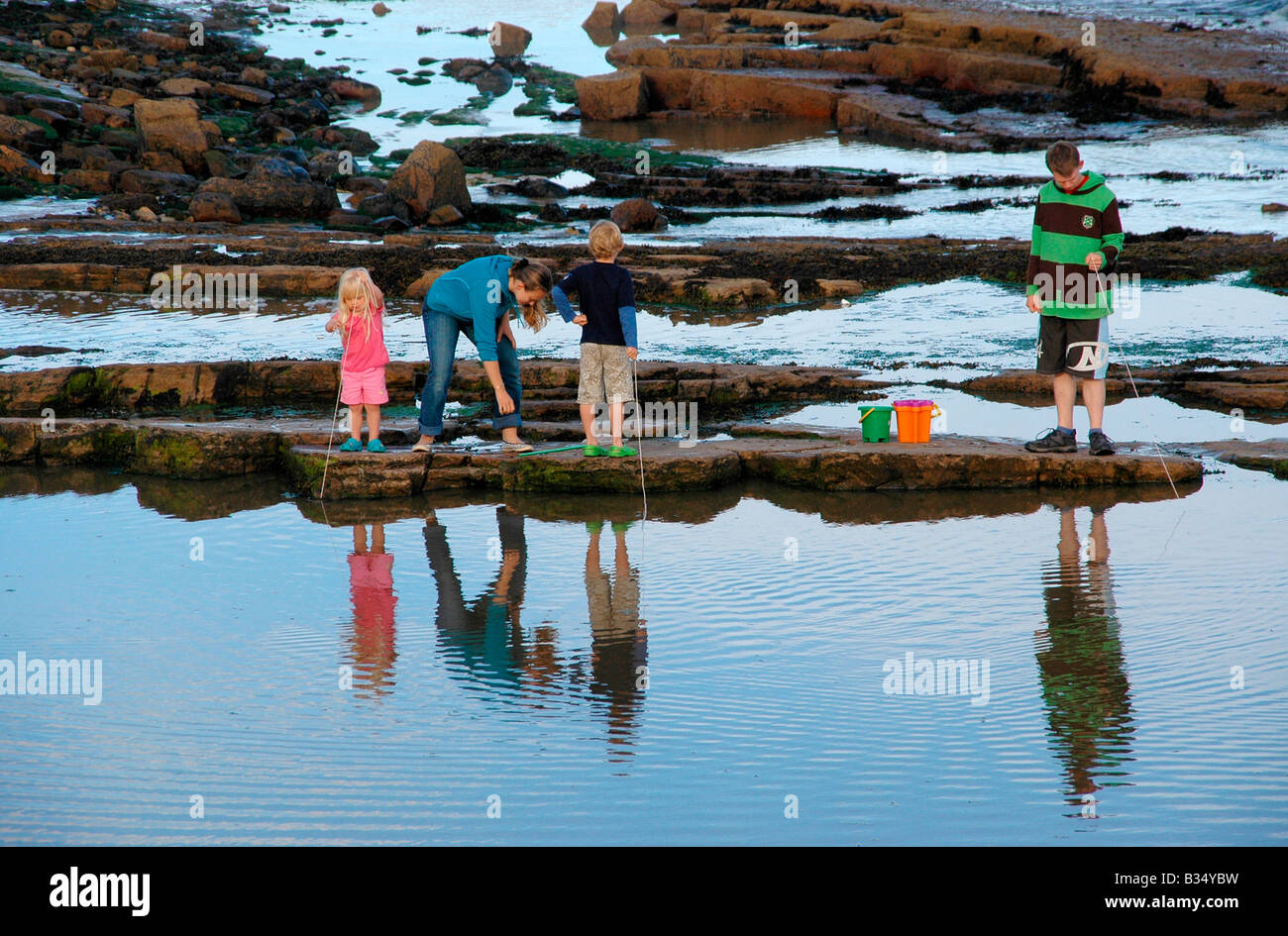 Eine junge Frau und Kinder Suche nach Krabben und Elritzen in Rock Pools - Fife, Ost-Schottland. Stockfoto
