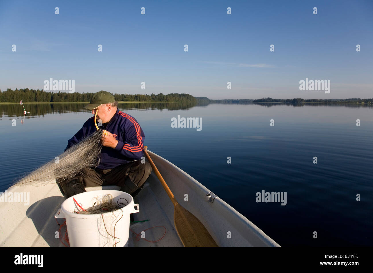 Älterer Mann überprüfen die Fischernetze am frühen Morgen, Finnland Stockfoto