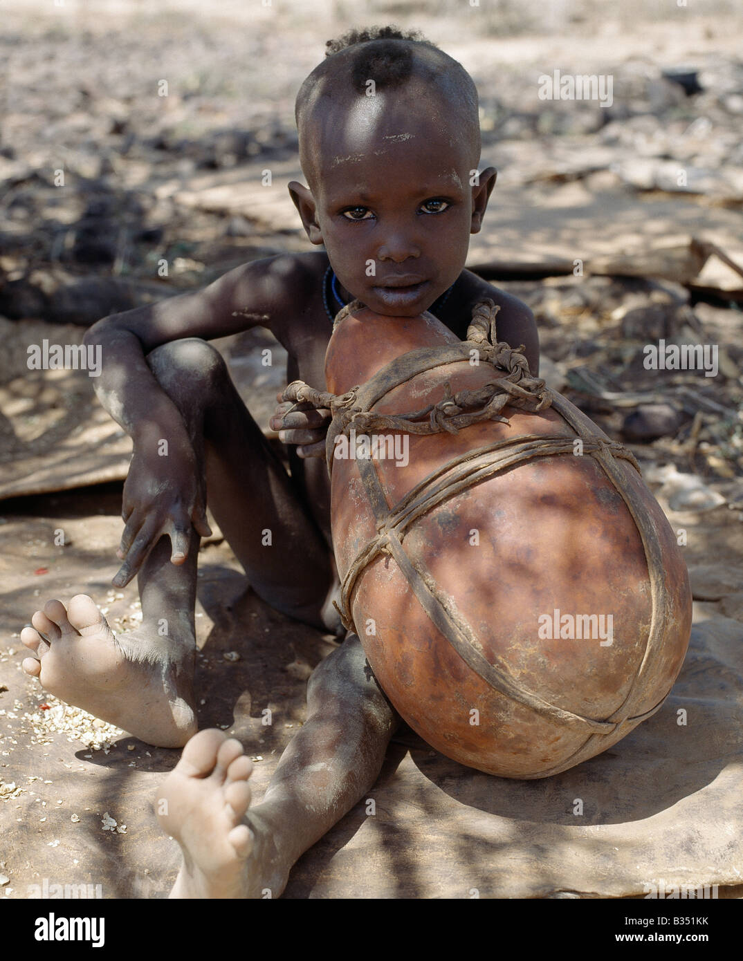 Kenia, Turkana, Lokori. Turkana Junge schaut nachdenklich, als er einen großen Kürbis hält. Kürbisse sind weniger häufig mit der Turkana als die hölzernen Behälter, die ihre Frauen machen; Erstens, sie sind teuer, da sie aus der Ferne gebracht werden müssen, aber noch wichtiger ist sie leichter unterwegs zu knacken. Stockfoto