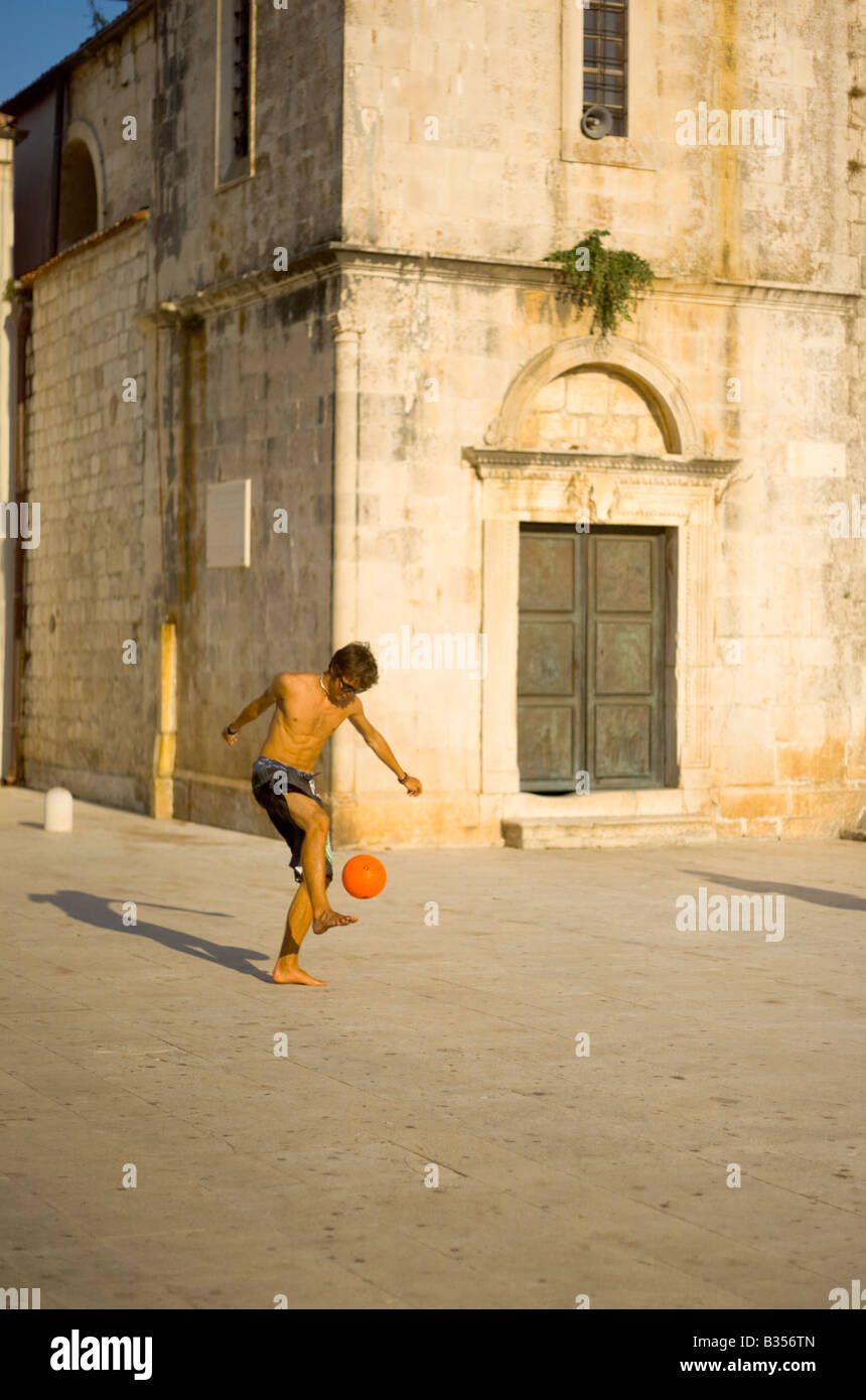 Junger Mann spielt Fußball außerhalb St. Stephans Kathedrale in Kroatien Hvar Town Square Stockfoto