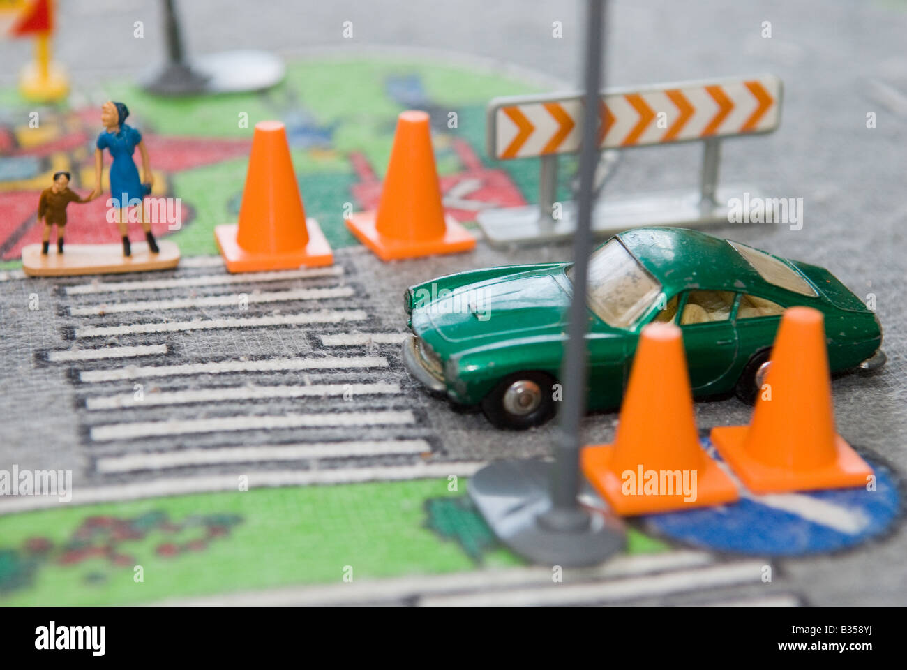 Mutter und Kind Straße überqueren. Leitkegel zeigen Straßenarbeiten. grünes Auto hält für sie zu überqueren. Still-Leben. Stockfoto