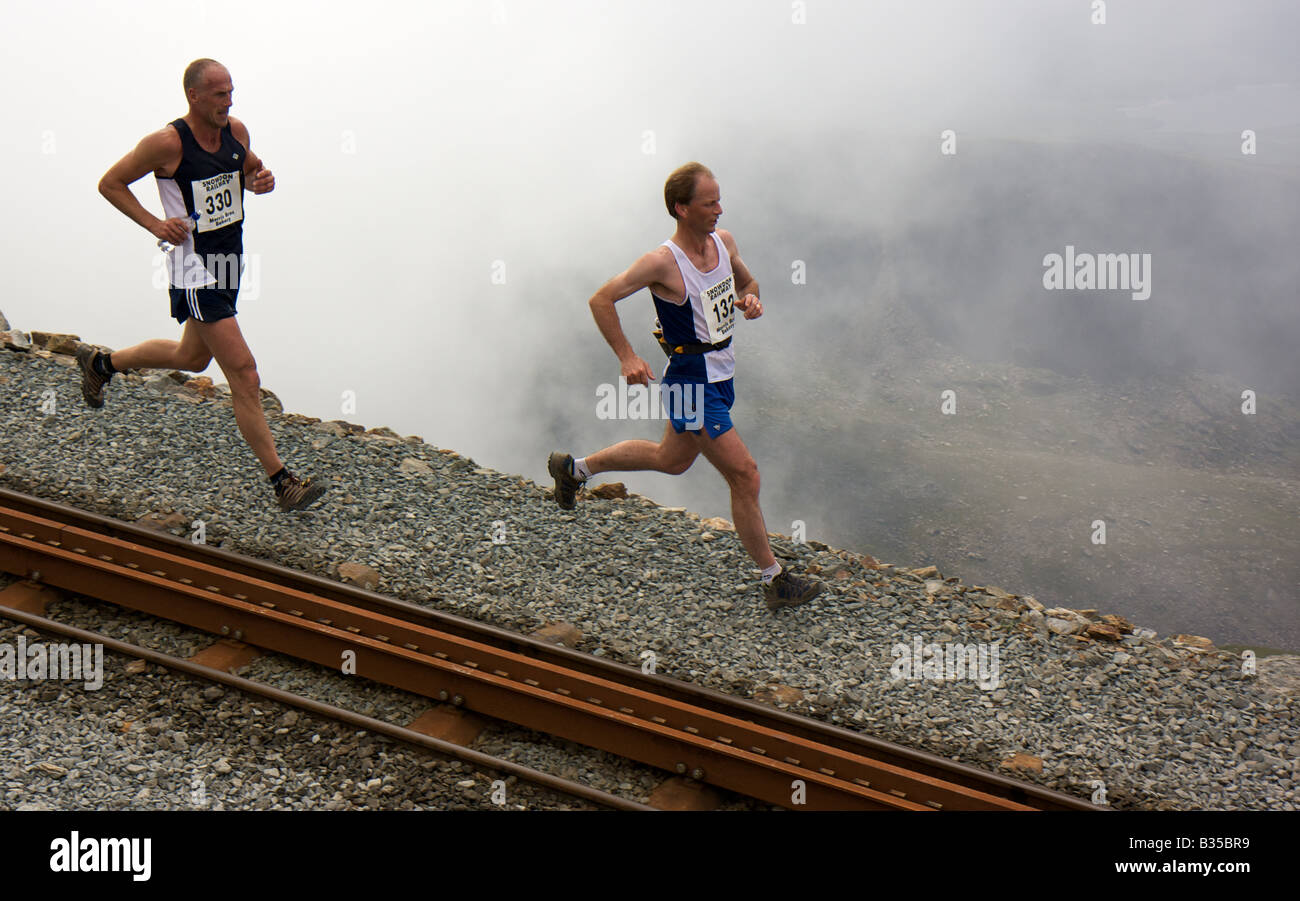 Zwei Läufer Racing Down neben Mount Snowdon Railway Track während des jährlichen Mount Snowdon-Rennens. Stockfoto