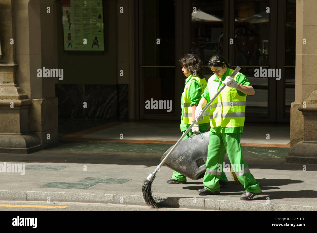 Spanien Barcelona zwei Frauen in hellen grünen Uniformen und Sicherheitswesten verwenden Besen sauber Bürgersteig und sammeln Müll Las Ramblas Stockfoto