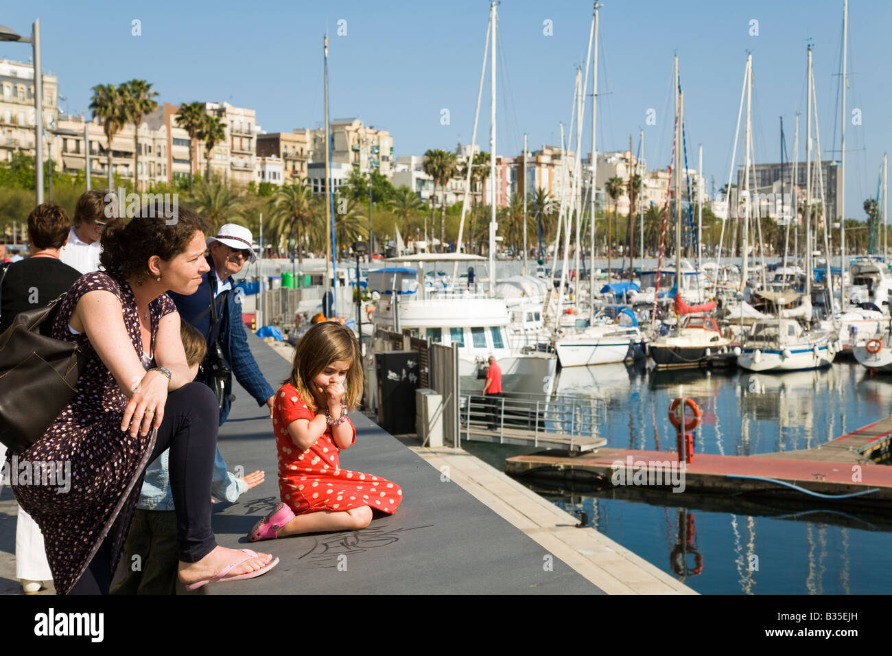 Spanien-Barcelona-Frau und zwei kleinen Kindern anzeigen Hafen Marina Port Vell Mädchen sitzen auf Betonwand mit Blick auf Segelboote Stockfoto