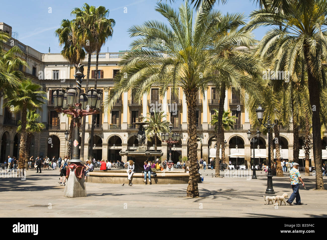 Spanien Barcelona Laternenpfahl entworfen von Antoni Gaudi Palmen und Brunnen im Placa Reial neoklassischen quadratische Plaza Mann zu Fuß Hund Stockfoto