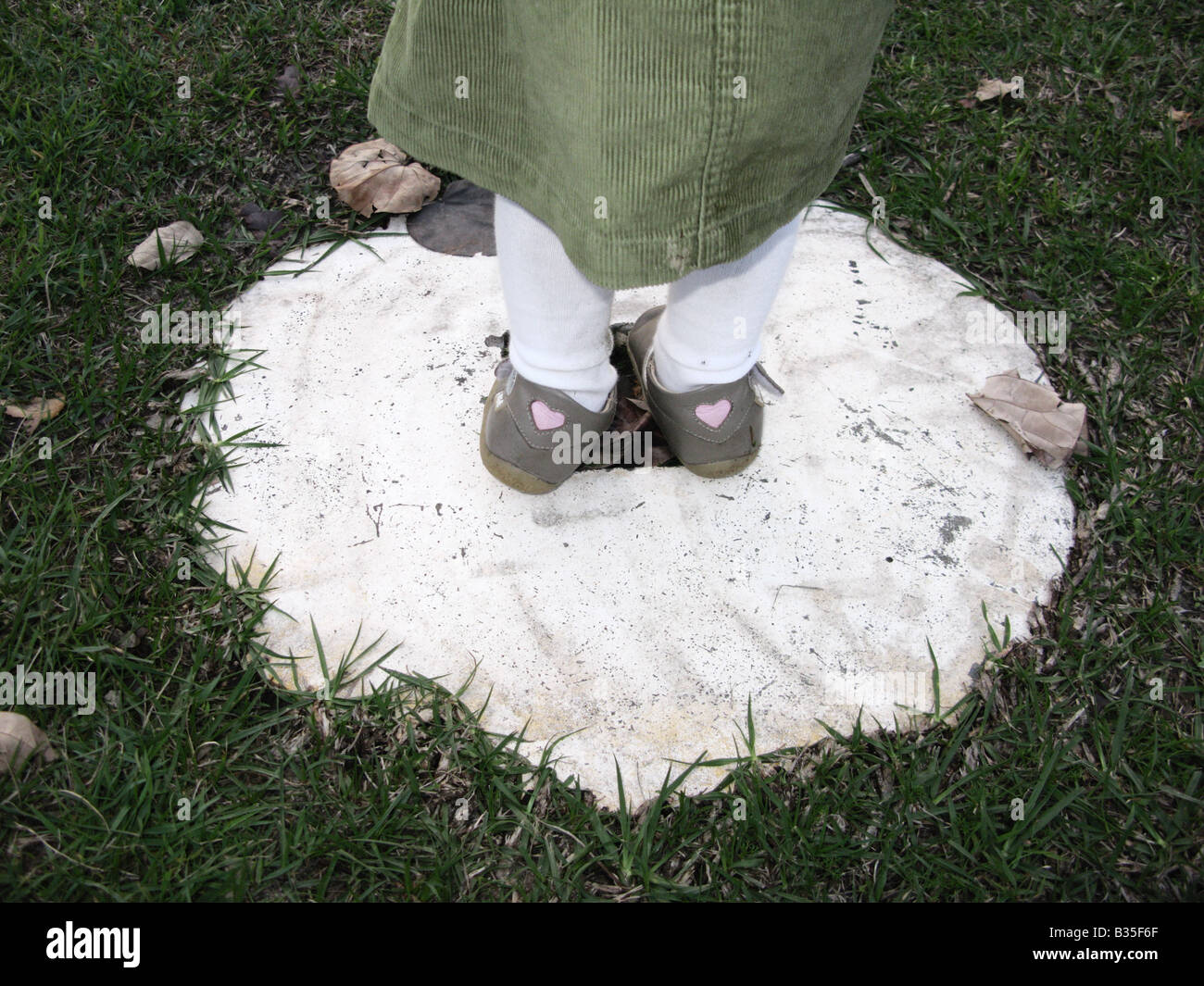 Nahaufnahme mit Childs Füße mit niedlichen Schuhe stehen auf einer Zement-Kreis Stockfoto