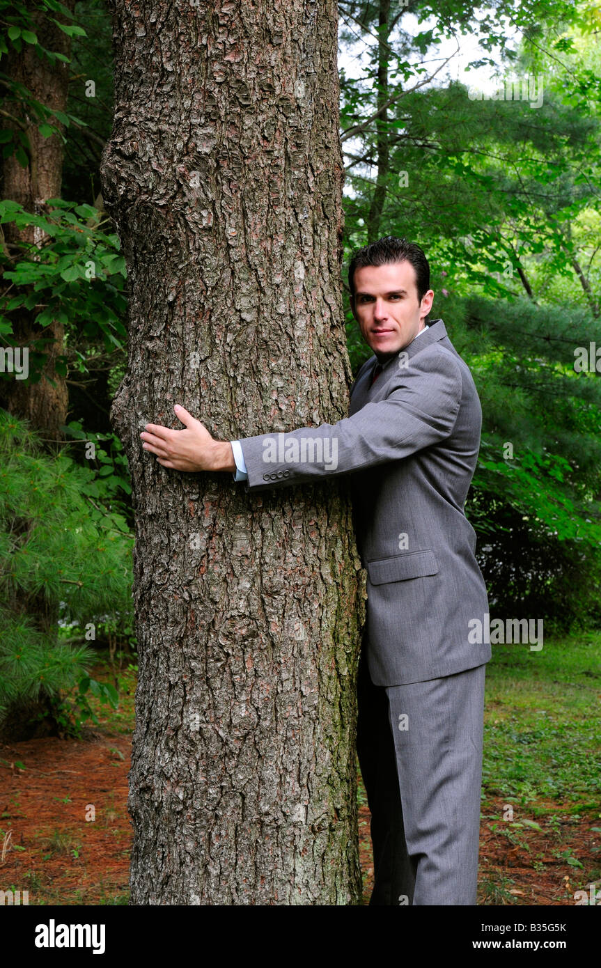 Ein Geschäftsmann im Anzug umarmt einen Baum darstellt, Treehugger und corporate Umweltschutz Stockfoto